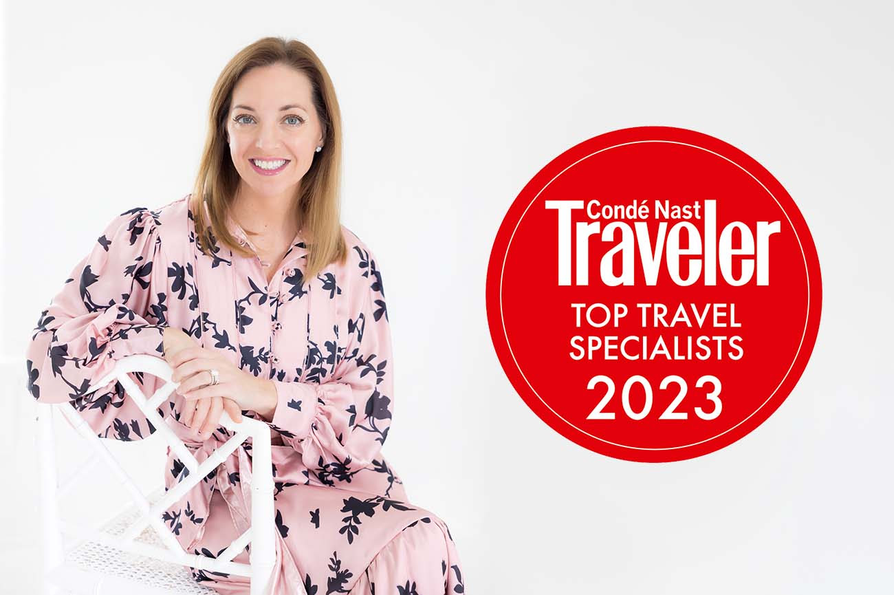 Top 2023 travel specialist by Conde Nast Travel sitting on a white lawn chair in a pink and black dress